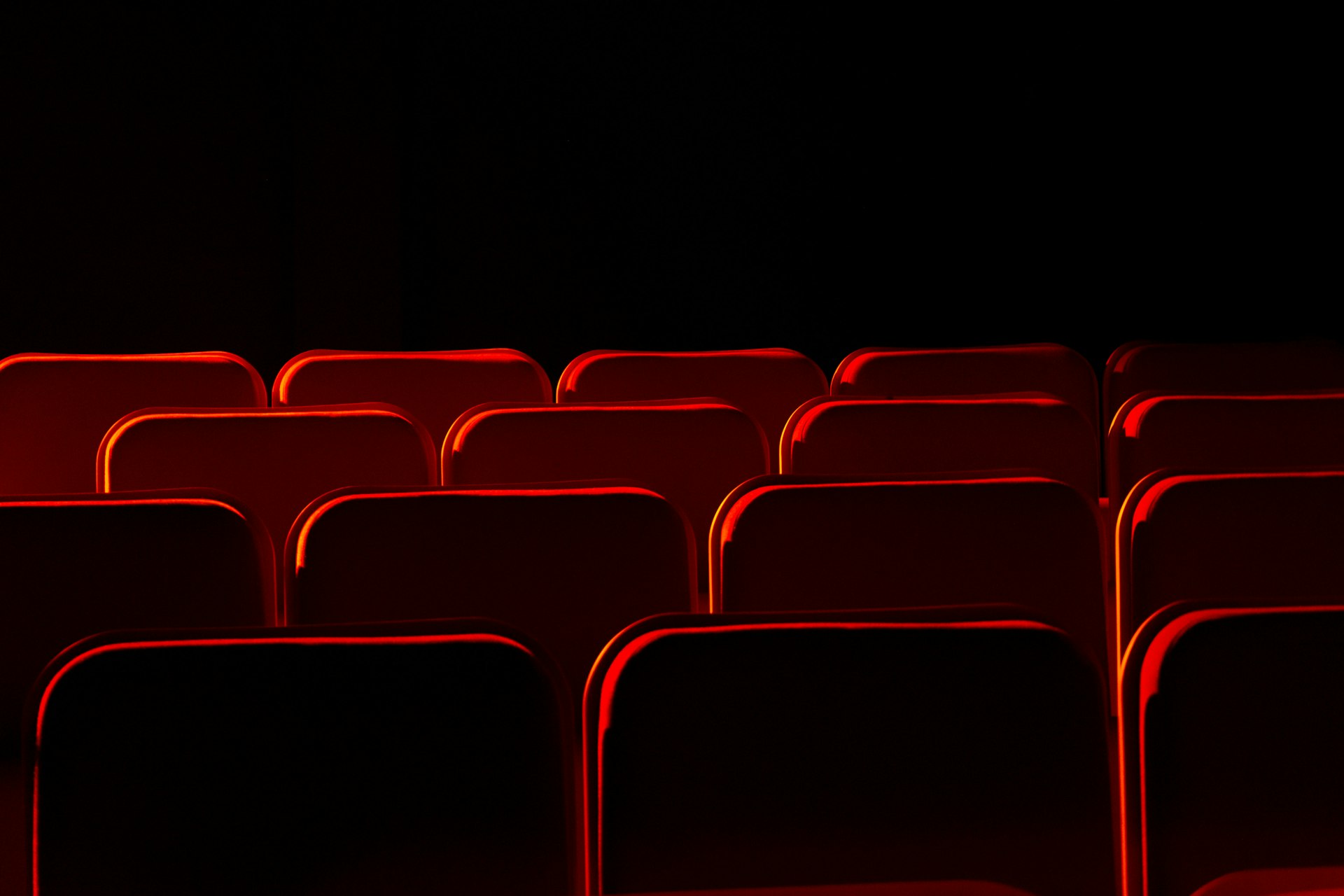 Rangées de fauteuils cerclés d'un liseré rouge dans une salle plongée dans le noir